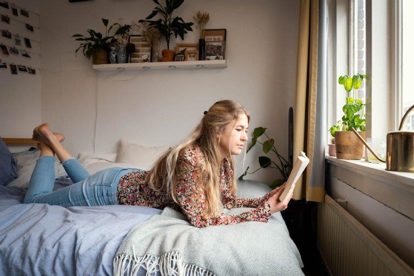 Sofia leest een boek op het bed in haar kamer