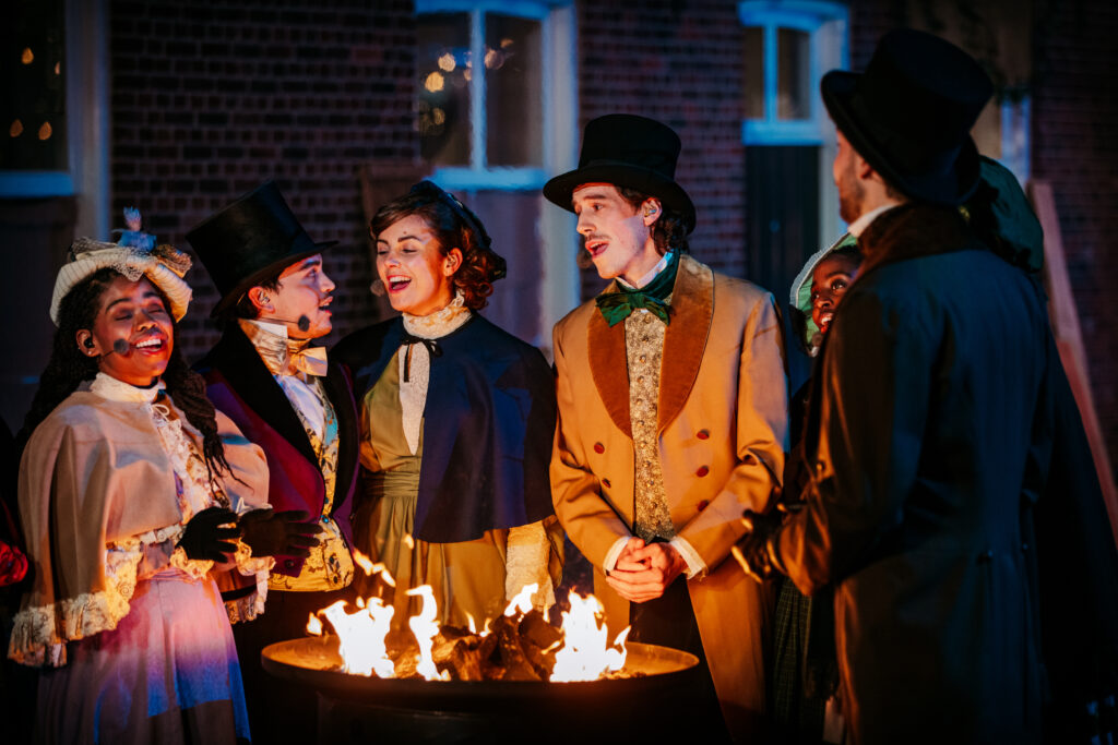 Koor tijdens Scrooge Live 2023 zingend bij kampvuur
