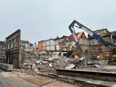 Zicht vanaf de Varkensstraat op de sloop van het pand Varkensstraat 17. Op de rechterzijde van de foto zijn de gestutte gevels aan de Rozemarijnsteeg zichtbaar.